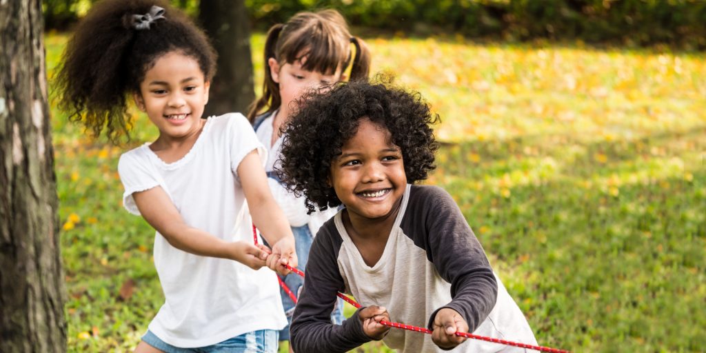 young children playing tug of war outside