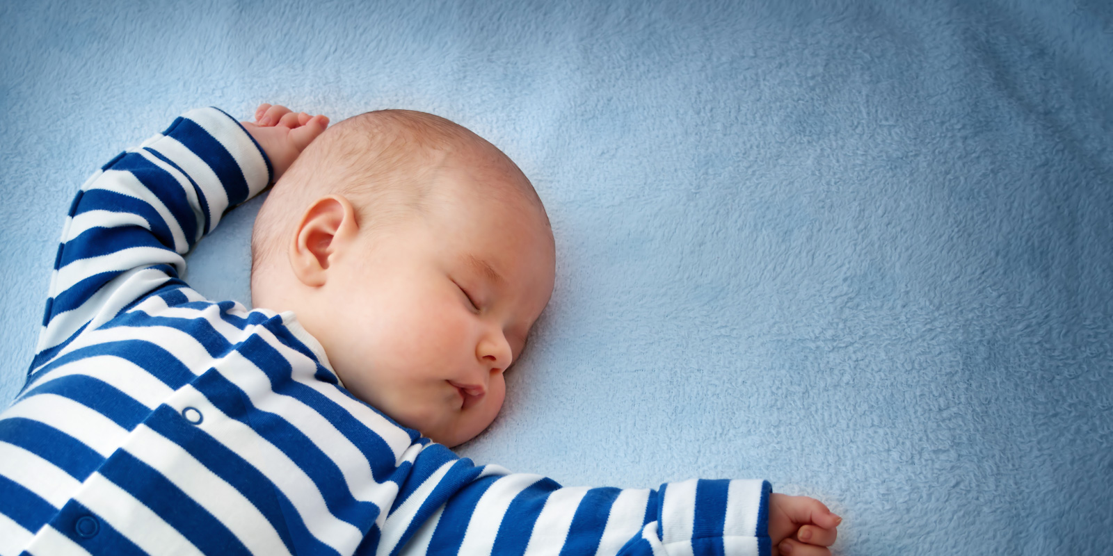 infant sleeping in crib with blue blanket
