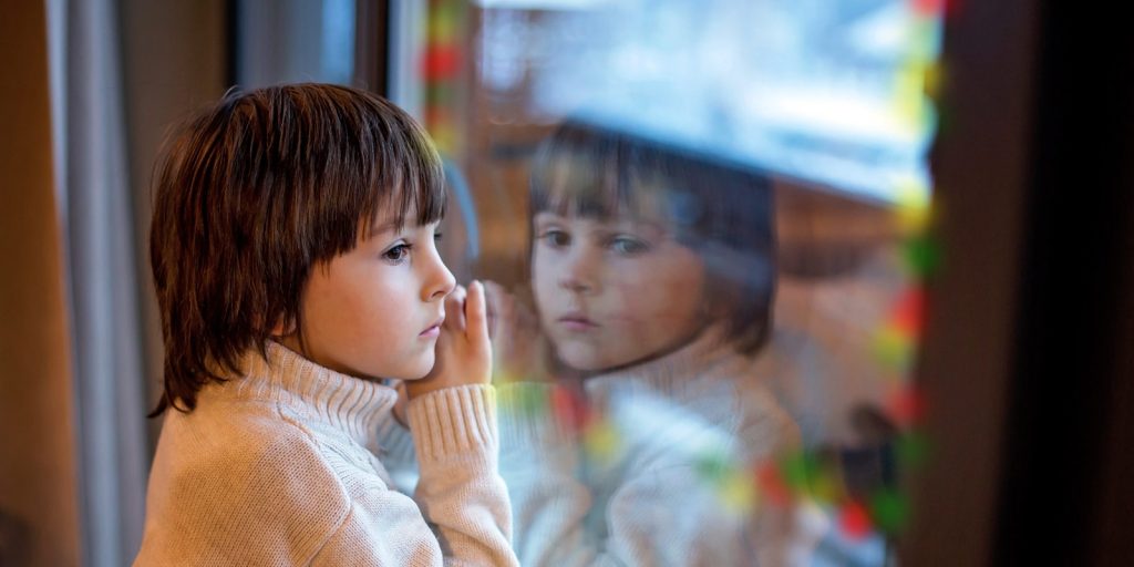 preschool boy looking through a window at Christmas lights