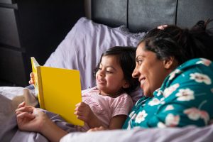 mother reading with daughter in bed