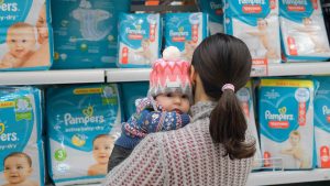 mother holding baby while shopping for diapers