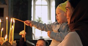 mother holding baby lights a candle